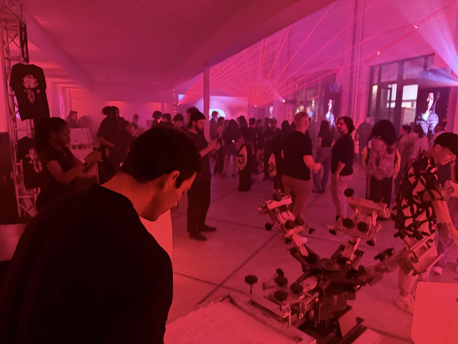 Large crowd at vibrant neon-lit indoor festival event with multiple attendees engaged throughout the venue